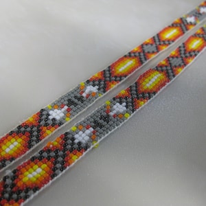 May include: Two beaded strips with a geometric pattern in shades of gray, orange, yellow, and white.