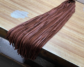 May include: A bundle of brown leather fringe, approximately 100 strands, for crafting projects.