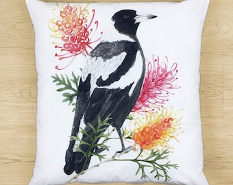 May include: A white pillow with a black and white magpie bird perched on a branch with pink and yellow flowers. The bird is facing right and has a black eye and beak.