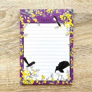 May include: Purple notepad with a lined white interior and a floral border. The border features yellow flowers and black birds. The notepad has the word "Notes" printed at the top.