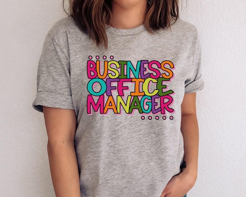 以下が含まれることがあります： カラフルな文字で「BUSINESS OFFICE MANAGER」と書かれたグレーのTシャツです。