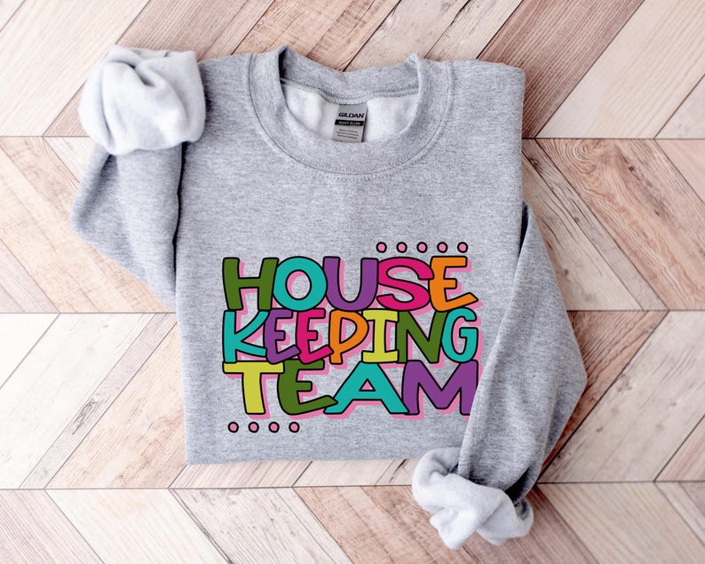 May include: Grey sweatshirt with the text "HOUSEKEEPING TEAM" in colourful, outlined letters.