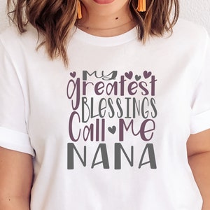 May include: White t-shirt with a purple and gray graphic that says "My greatest blessings call me Nana".