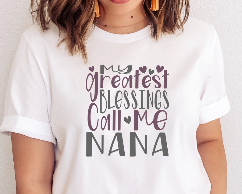 May include: White t-shirt with a purple and gray graphic that says "My greatest blessings call me Nana".