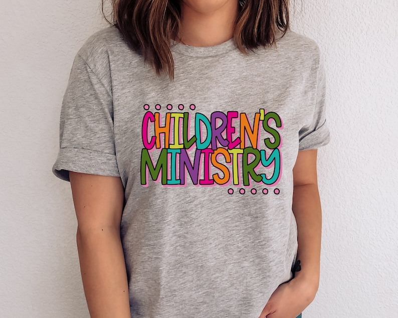 May include: A gray t-shirt with the text "CHILDREN'S MINISTRY" in colorful letters. The letters are outlined in black and have a playful, hand-drawn style.