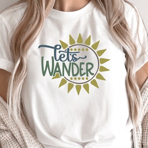 May include: White t-shirt with a green and blue graphic of a sun with the text "Let's Wander" inside.