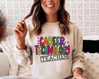 Puede incluir: Una sudadera beige claro con el texto "CAREER TECHNOLOGY TEACHER" en letras de colores y contorneadas.
