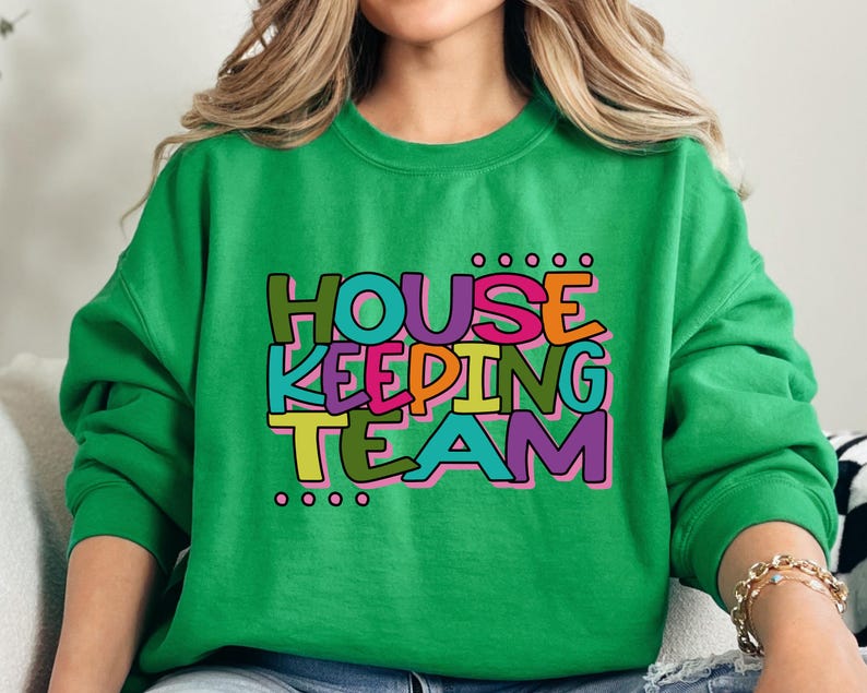 May include: Green sweatshirt with the text "HOUSEKEEPING TEAM" in colourful letters.