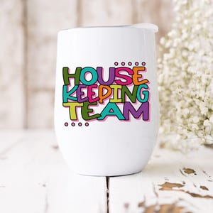 May include: White stainless steel wine tumbler with a colourful graphic that says "Housekeeping Team".