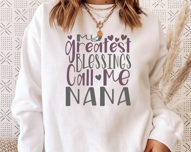 May include: White sweatshirt with the text "My greatest blessings call me Nana" in purple and gray lettering with small hearts.