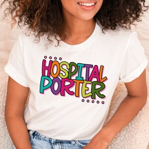 May include: A white t-shirt with the text "HOSPITAL PORTER" in colorful, outlined letters. The letters are in a playful, cartoon-like font.