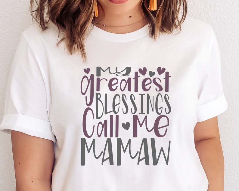 Peut inclure: T-shirt blanc avec un graphique violet et gris qui dit "Mes plus grandes b&eacute;n&eacute;dictions m'appellent Mamaw".