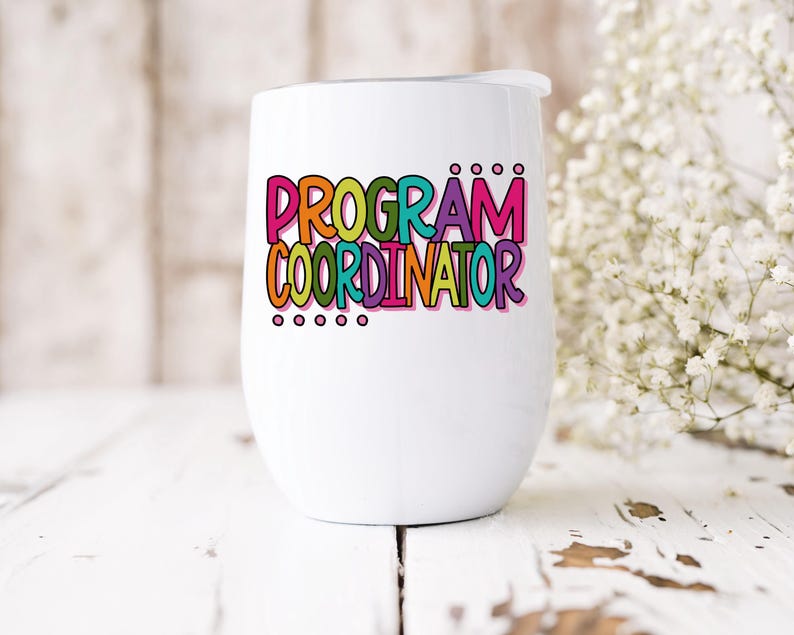 May include: A white insulated wine tumbler with a lid. The tumbler features the words "PROGRAM COORDINATOR" in colorful, bubble-style letters. The design includes a variety of colors, including pink, orange, green, and purple. The tumbler is on a white wooden surface.