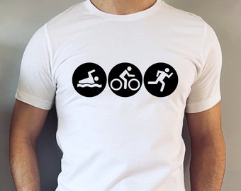 May include: White t-shirt featuring three black circles with white icons representing swimming, cycling, and running. The shirt is made of a soft, lightweight material, perfect for athletic activities or casual wear.