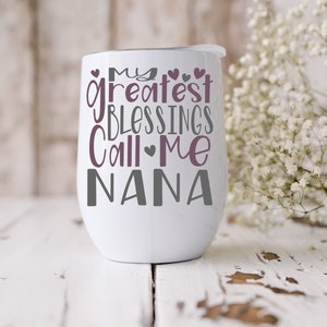 May include: White stainless steel wine tumbler with a purple and gray design that reads "My Greatest Blessings Call Me Nana".