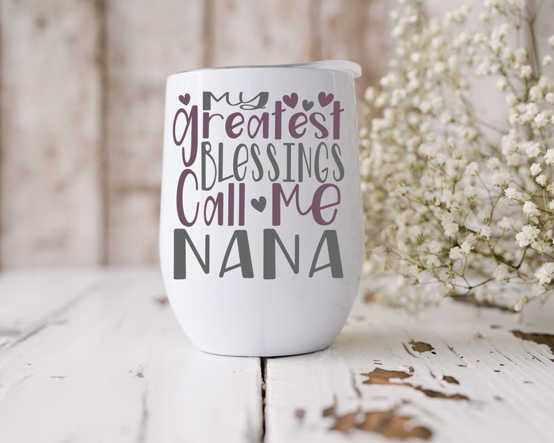 May include: White stainless steel wine tumbler with a purple and gray design that reads "My Greatest Blessings Call Me Nana".