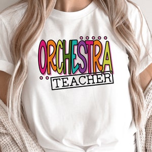 May include: White t-shirt with the text "ORCHESTRA TEACHER" in colorful letters.