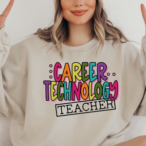 May include: A beige sweatshirt with the text "CAREER TECHNOLOGY TEACHER" in colorful, outlined letters.