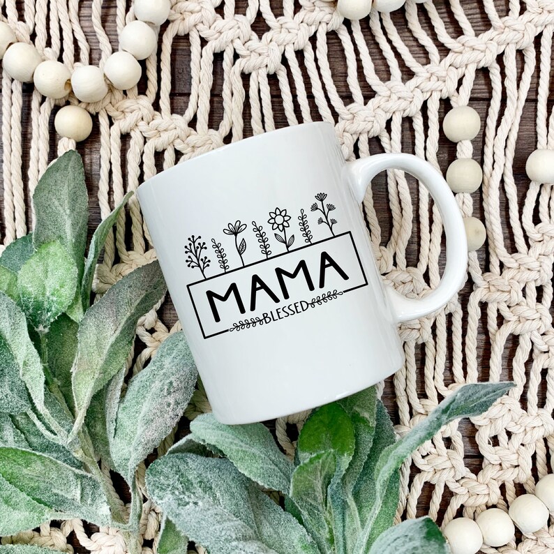 May include: White ceramic mug with a black design of flowers and the text "MAMA BLESSED".
