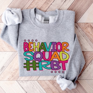 May include: Gray sweatshirt with the text "BEHAVIOR SQUAD #RBT" in colorful letters.
