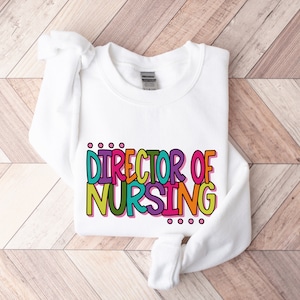May include: White sweatshirt with the text "DIRECTOR OF NURSING" in colorful, outlined letters.