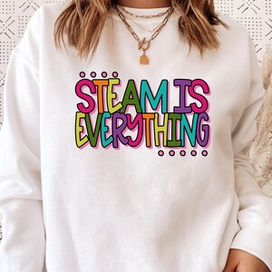 Może przedstawiać: Biała bluza z kolorowym nadrukiem, na którym widnieje napis "STEAM IS EVERYTHING".