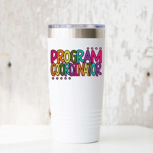 May include: A white insulated tumbler with a silver lid. The tumbler features the words "PROGRAM COORDINATOR" in colorful bubble letters. Below the text are five small black dots. The tumbler is designed to keep beverages hot or cold.