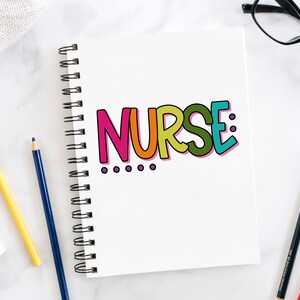 Peut inclure: Un carnet blanc avec une reliure spirale. Le mot "NURSE" est &eacute;crit en lettres color&eacute;es sur la couverture du carnet. Il y a quatre points violets sous le mot.