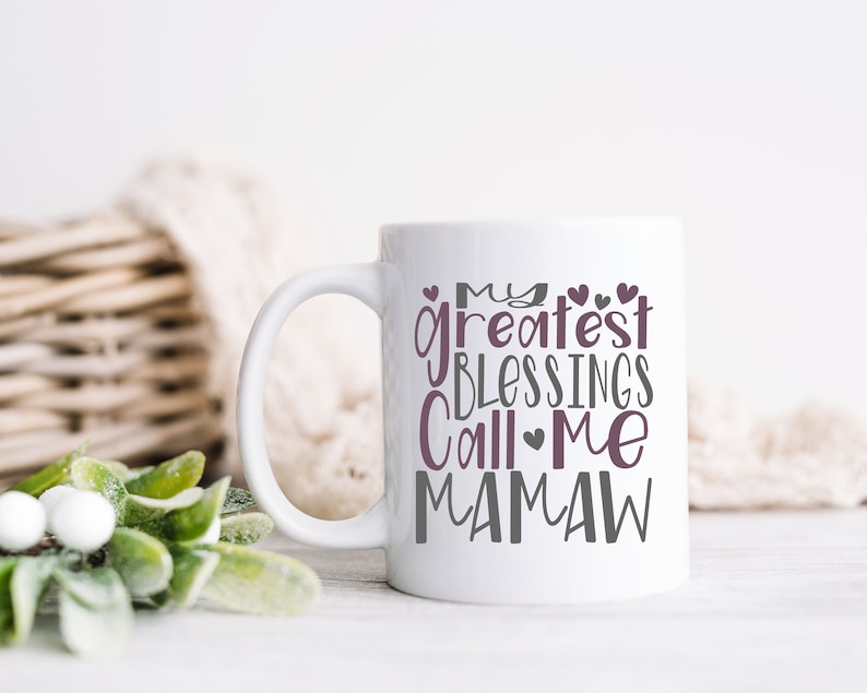 Peut inclure: Une tasse en c&eacute;ramique blanche avec un motif gris et violet qui dit "Mes plus grandes b&eacute;n&eacute;dictions m'appellent Mamaw".