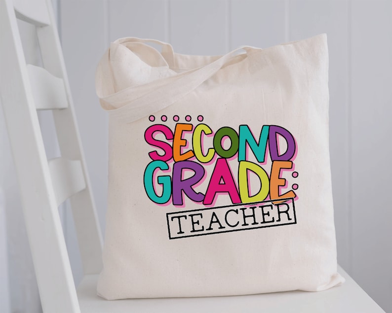 May include: A white canvas tote bag with the text "Second Grade: Teacher" in colorful letters. The letters are outlined in black and have a playful, hand-drawn style.