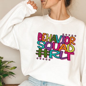 May include: White sweatshirt with a colorful graphic that says "Behavior Squad #RLT".