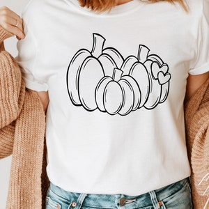 May include: A white t-shirt with a black line drawing of a group of pumpkins with hearts on the largest pumpkin.