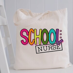 May include: A white canvas tote bag with the words "SCHOOL NURSE" in colorful, outlined letters. The word "SCHOOL" is in rainbow colors and the word "NURSE" is in a black rectangle.