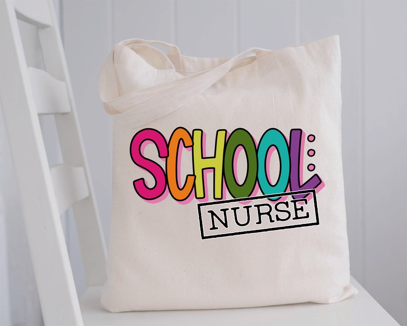May include: A white canvas tote bag with the words "SCHOOL NURSE" in colorful, outlined letters. The word "SCHOOL" is in rainbow colors and the word "NURSE" is in a black rectangle.