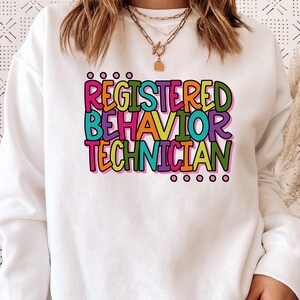 May include: White sweatshirt with a colorful graphic that reads "Registered Behavior Technician".