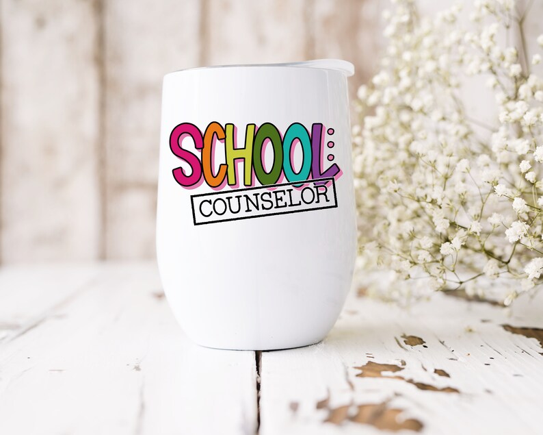 以下が含まれることがあります： 白いステンレス製のタンブラーに、カラフルな「SCHOOL COUNSELOR」のデザインが施されています。タンブラーには蓋が付いており、白い木製の表面の上に置かれています。