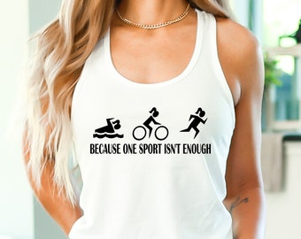 Puede incluir: Camiseta blanca de tirantes con un gráfico negro de tres figuras femeninas que representan la natación, el ciclismo y la carrera. El texto "Because one sport isn't enough" está impreso debajo de las figuras.