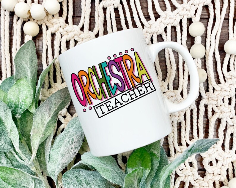May include: White ceramic mug with a colorful graphic that says "ORCHESTRA TEACHER".
