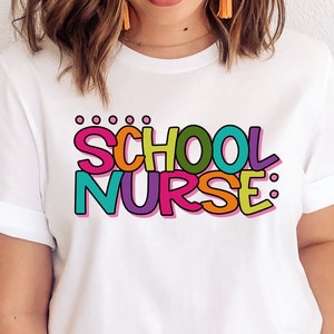 May include: White t-shirt with the text "SCHOOL NURSE" in colorful, outlined letters.