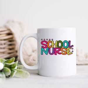 May include: White ceramic mug with a colorful graphic that says "SCHOOL NURSE:" in a playful font.