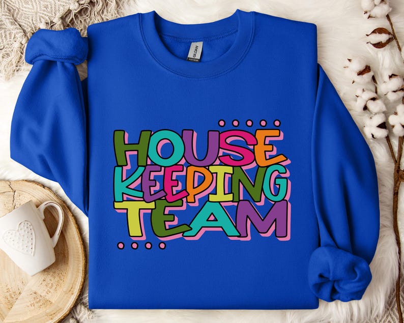 May include: A royal blue sweatshirt with the text "HOUSE KEEPING TEAM" in colourful, playful lettering.
