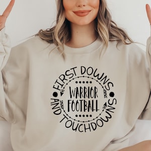 May include: A beige sweatshirt with a black circle graphic that says "First Downs and Touchdowns Warrior Football".