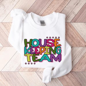 May include: White sweatshirt with the text "HOUSE KEEPING TEAM" in colourful letters.