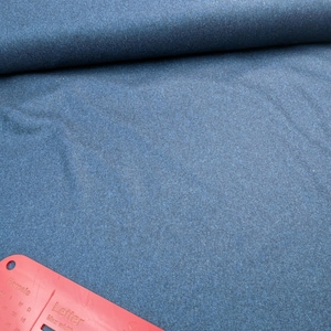 May include: A roll of dark blue fabric with a textured surface. A red plastic ruler is in the foreground with the text "Letter" and "Large Letter". The fabric is likely used for sewing or crafting projects.