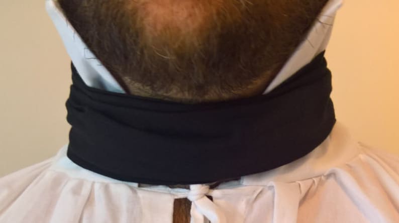May include: A black neck scarf worn over a white shirt with a white collar.