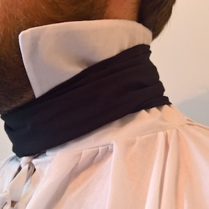 May include: A white shirt with a black fabric necktie. The necktie is folded over and tied at the neck.