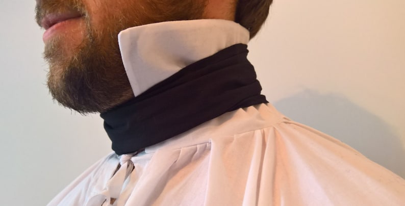 May include: A white shirt with a black fabric necktie. The necktie is folded over and tied at the neck.
