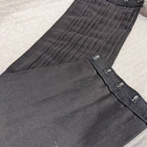 May include: Black fabric corset with multiple rows of metal hooks and eyes for adjusting the fit.