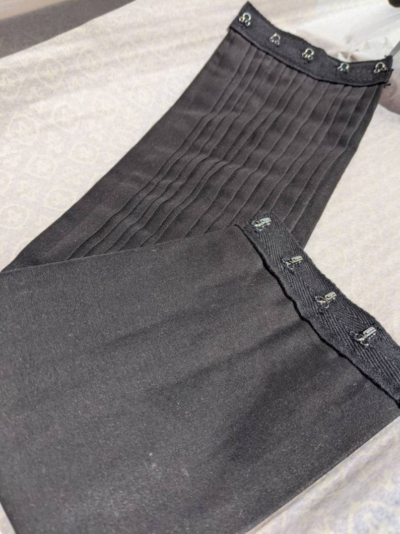 May include: Black fabric corset with multiple rows of metal hooks and eyes for adjusting the fit.