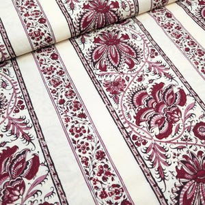 May include: White fabric with vertical stripes of a burgundy floral pattern. The floral pattern features intricate details and a paisley-like design.